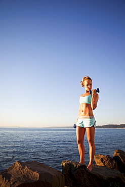 Athletic woman lifting weights outdoors