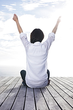 Woman sitting on porch with her arms raised