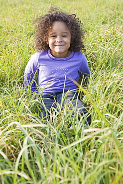 Young girl sitting in tall grass