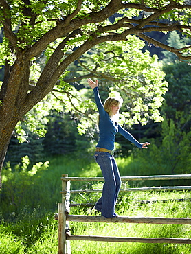 Young woman balancing on fence