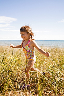 Beaver Island, Girl running in grass on beach, Beaver Island, Michigan, USA