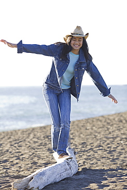 Teenage girl balancing on driftwood