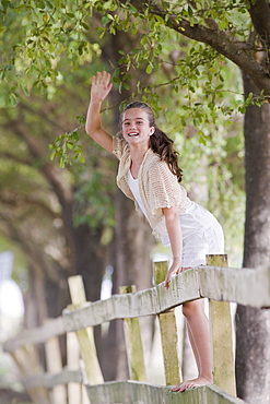 Girl standing on fence waving