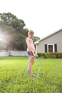 Girl standing in backyard with hula hoop