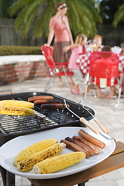 Grilled hotdogs and corn on backyard grill