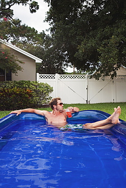 Man relaxing in inflatable swimming pool