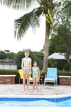 Girls standing at edge of swimming pool