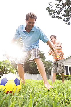 Father and son playing soccer in backyard