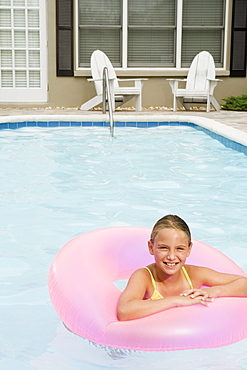 Girl floating on inflatable ring in swimming pool