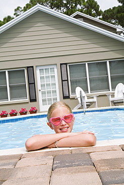 Girl leaning on edge of swimming pool