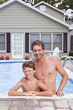 Father and son posing in swimming pool