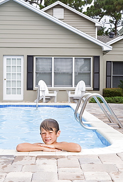 Boy leaning on edge of swimming pool