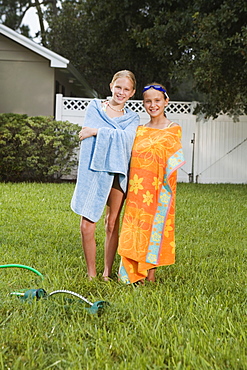 Girls wrapped in towels on lawn