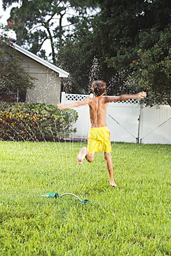 Boy running through sprinklers