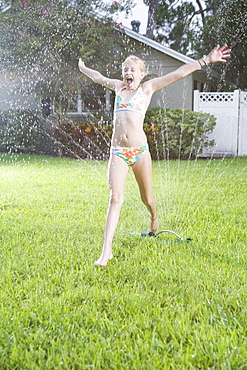 Girl running through sprinklers