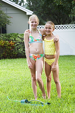 Girls playing with sprinkler in backyard