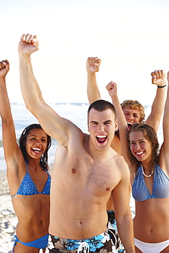 Young friends raising arms on beach