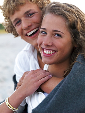 Young couple wrapped in blankets on beach