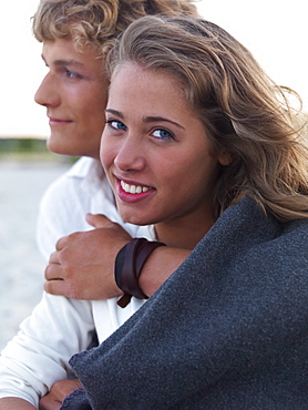 Young couple wrapped in blankets on beach