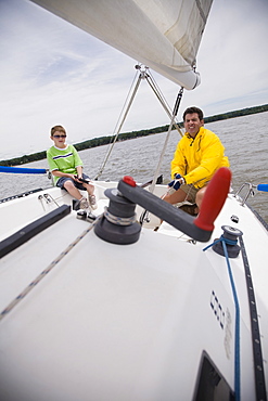 Father and son sitting on sailboat