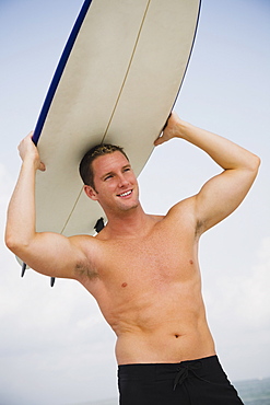 Bare-chested man holding surfboard