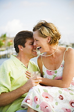 Woman laughing while husband bites necklace