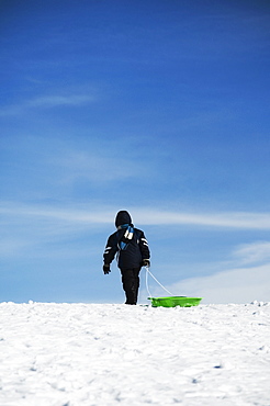 Child pulling sled on snow