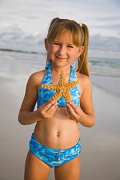 Girl holding up starfish, Florida, United States