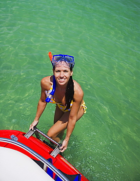 Woman in snorkeling gear climbing off boat, Florida, United States