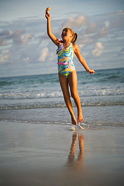 Girl jumping in ocean surf, Florida, United States