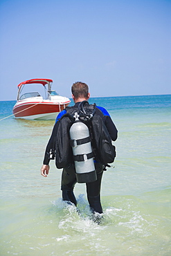 Man carrying scuba gear towards boat, Florida, United States