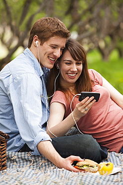 Young couple with mp3 player in orchard