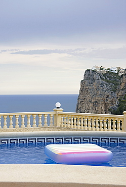 Spain, Costa Blanca, Swimming pool on terrace, sea and cliff in background