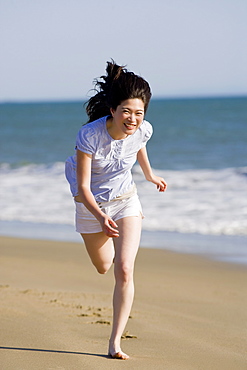 USA, California, Point Reyes, Young woman running on beach