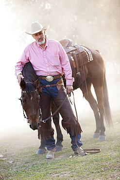 Portrait of senior man with horse in ranch