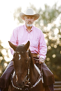 Portrait of senior man horseback riding in ranch