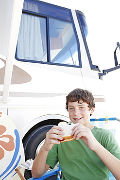 Portrait of boy eating sandwich outside motor home