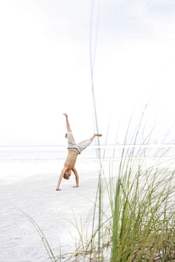 Boy doing cartwheel on beach