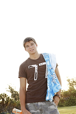 Teenage boy carrying beach towel on shoulder