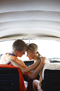 Young couple sitting in van on beach