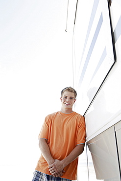 Young man leaning against motor home