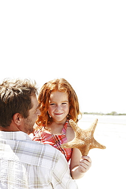 Father carrying daughter and starfish