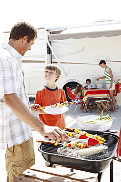 Man grilling dinner for family on beach