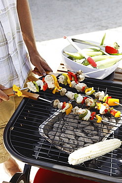 Man grilling shish kebabs and corn