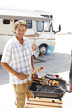 Man grilling shish kebabs on beach