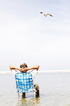 Man relaxing in lounge chair in middle of water