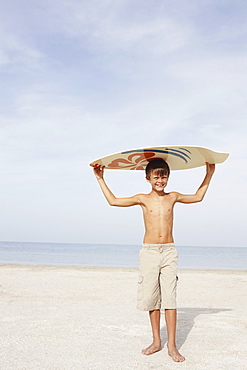 Boy holding skimboard on beach