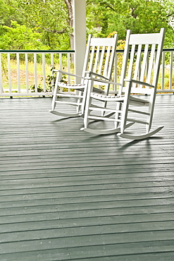 Two white rocking chairs on porch