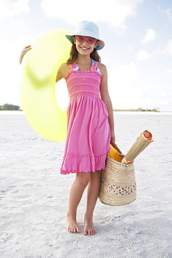 Portrait of girl holding inflatable tube and bag on beach