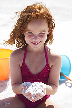 Girl digging in sand on beach